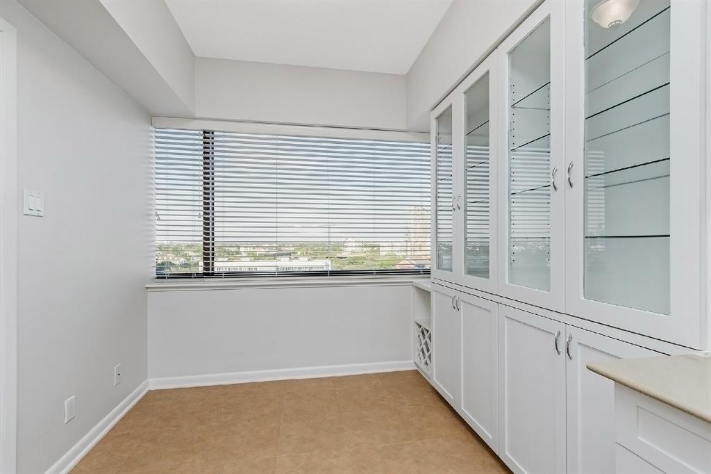 An optimal breakfast area that can handle a crowd when preparing meals. This gathering space is complete with the Museum District landscape by the window, custom blinds, crown molding, and custom cabinet and shelves.