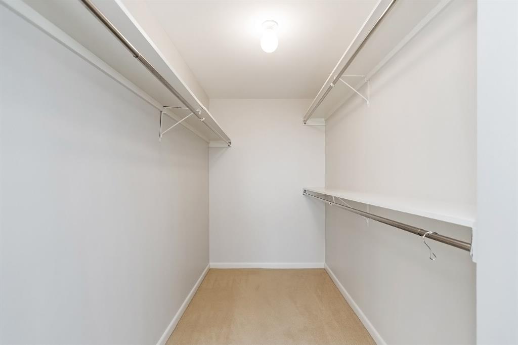 An excellent walk-in closet made for a dedicated and stylish shopper. It includes hanging rods, a wall-mounted counter, and ceiling light to maximize its functionality. The wide space makes dressing up and organizing much convenient and easier.
