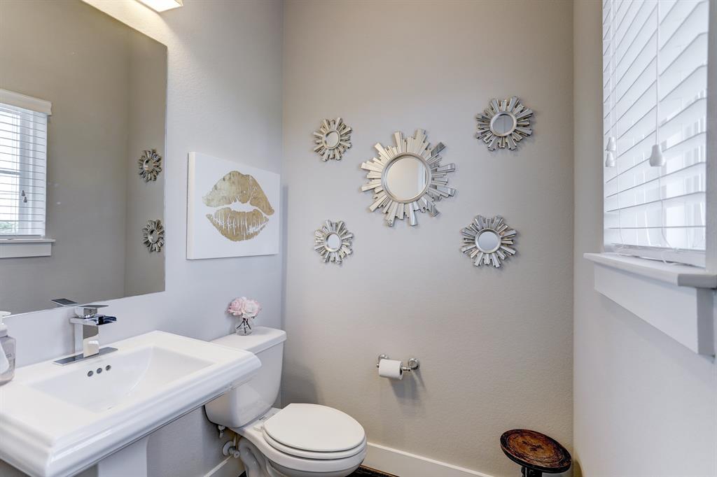 Highlights of the elegantly modern powder room include a pristine stand-alone sink and a vanity mirror, as well as a window which lets natural light in, illuminating the entire area.