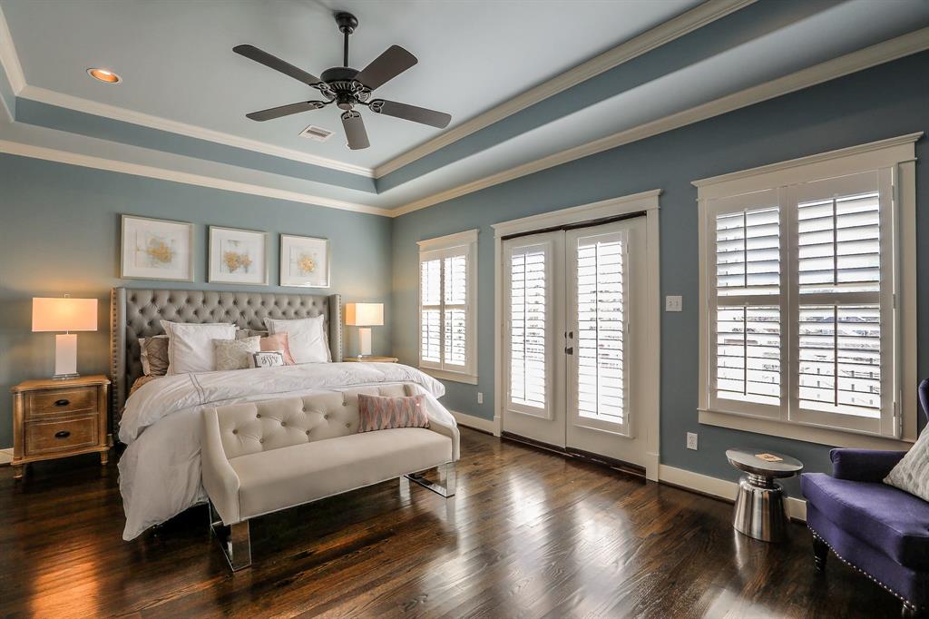 Spacious master suite features a recessed ceiling, crown molding, wood floors and plantation shutters.