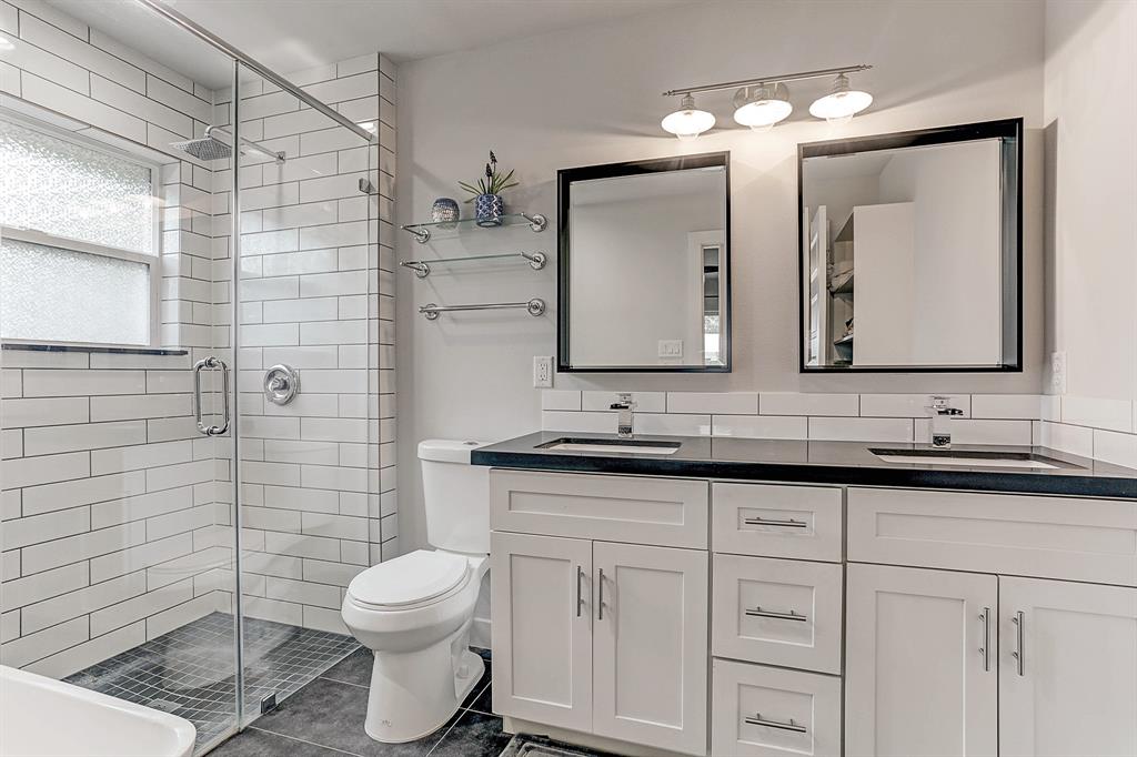 Updated master bathroom features dual vanity sink, ample storage space, luxurious bathtub and glass shower with subway tile back splash.