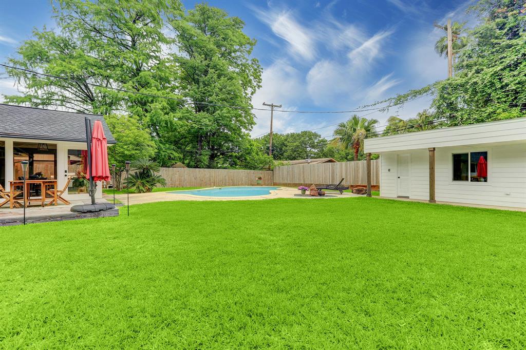 View of large backyard with new fencing and remodeled pool house.