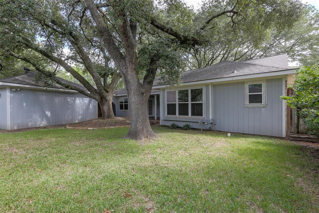 Fully fenced back yard with mature oak trees and covered patio.