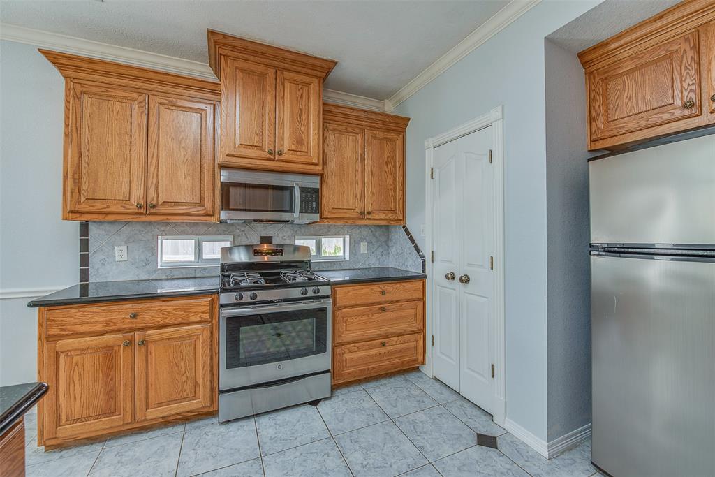 Small "peek" picture windows line either side of the kitchen's gas stove with microwave oven over head. A pantry separates the oven from the fridge that conveys.
