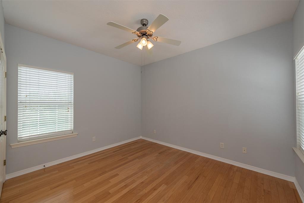 The back left-side bedroom is well lit with its two large windows and overhead ceiling fan with light fixture.