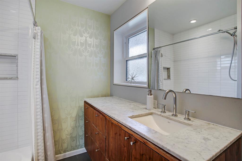Mid-century modern bathroom is full of character with a subway tiled shower with marble trimmed shower niche, period vanity with marble counter top modern faucet, and tile floors. New window features rain glass finish for privacy.