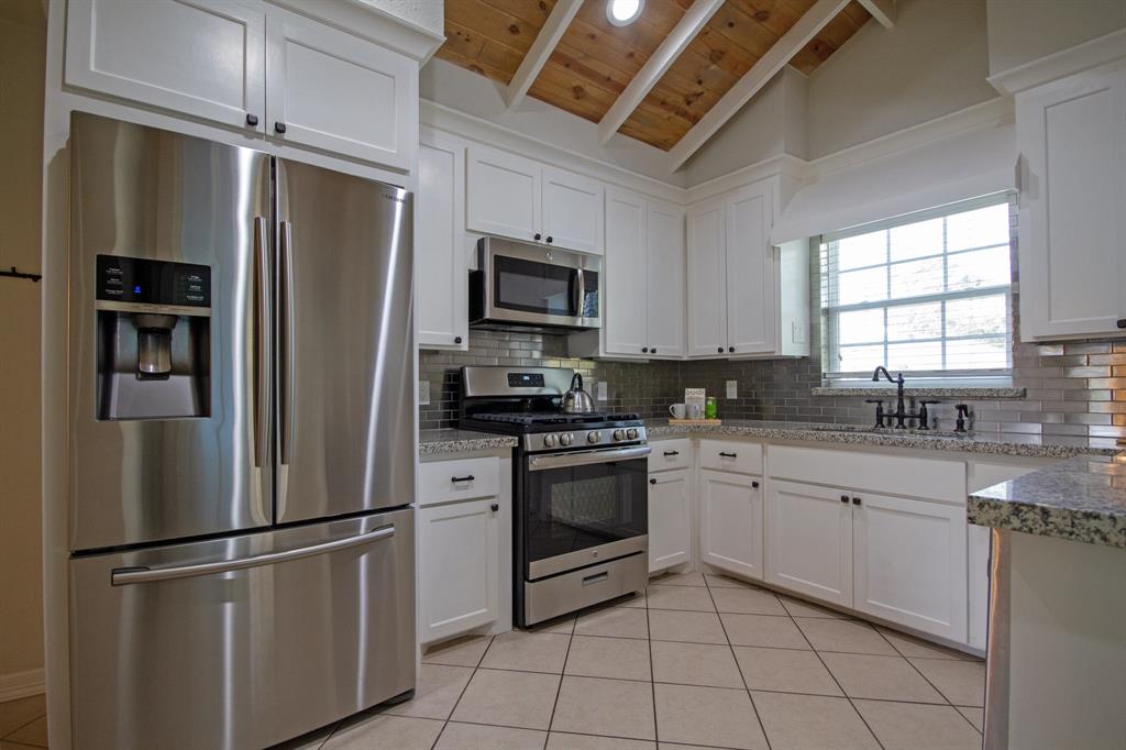 Open kitchen features full stainless steel appliance package and wooden ceiling accents