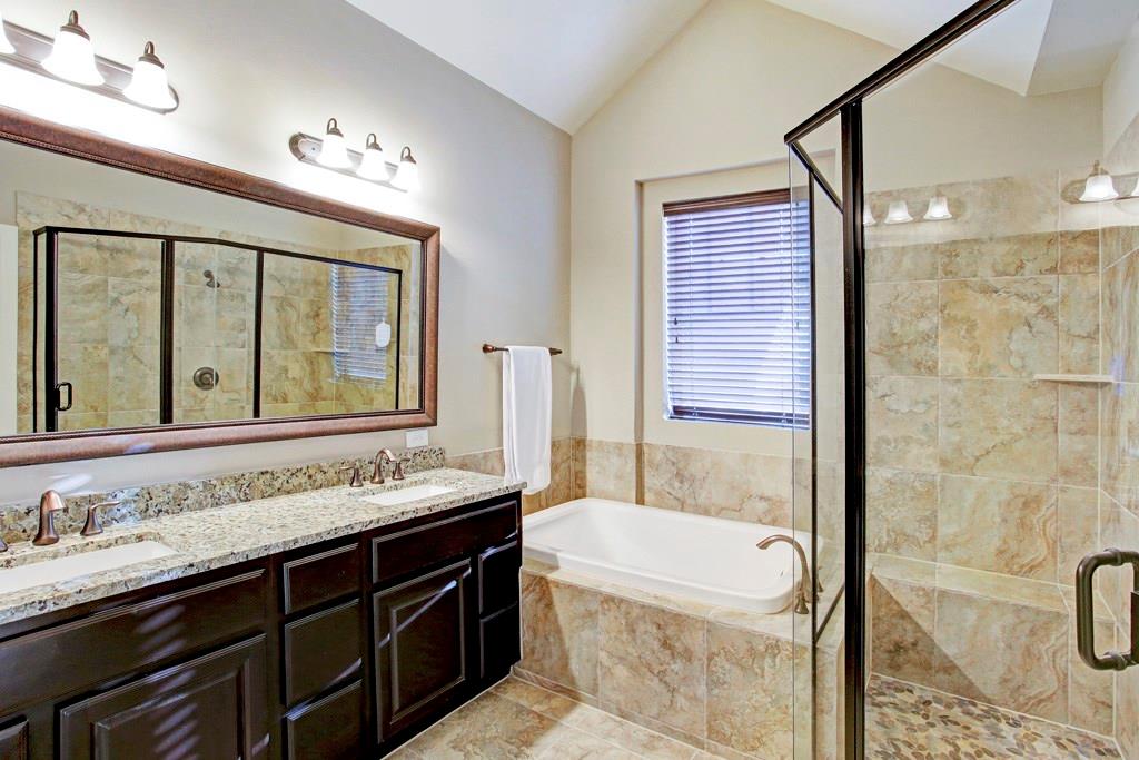 The handsome master bathroom. Large, glass walk-in shower, tub, dual sinks, decorative mirror and plenty of counter space.