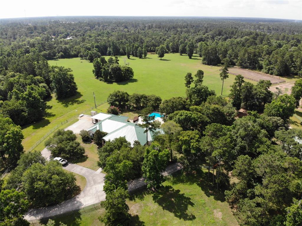 10525 Superior Lane Magnolia, Texas Imagine your ranch 5 minutes from the Woodlands and Magnolia!
This 160/253 acre ranch is located west of the Woodlands off of Superior Rd. The ranch is a mix of hardwoods and improved pastures, pond and 3 more stock tanks. The wonderful one story 4 bedroom, 4.5 bathroom limestone rock house (4931 sq. ft.) built in 2000 with a metal seamed roof sits up on a hill with big hardwoods surrounding the circular drive, a large pool, sport court, and 1433 square foot of covered -wrap around porches and a 4 car garage big enough for trucks and a golf cart garage. A 2 stall barn with room for 6 stalls near the house for horses and a board fenced riding arena.There are three more all metal free span construction buildings along the main road ideal for hay, livestock, heavy equipment, and any major workshops needed adding up to 21,00 sq. ft..The land is sandy soil and rolling pastures ideal for horses and cattle and great hay production.