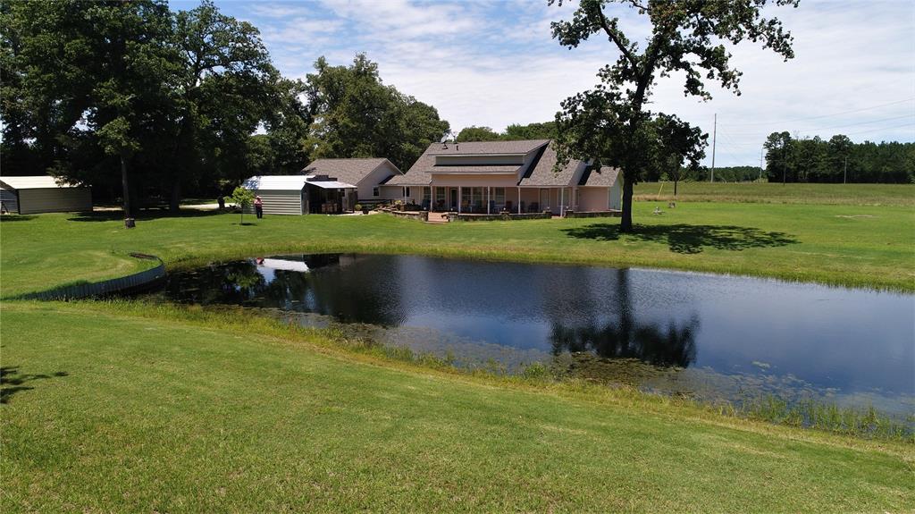 3999 An County Road 174 Grapeland, Texas This gorgeous custom home is situated on 26.602 pristine acres.The large living area has a nice built-in entertainment center and the hickory hardwood hand scraped floors throughout the living, kitchen, and dining area are to die for! The island kitchen is has granite counter-tops, tons of custom cabinets, and stainless appliances for the cook in the family. The master suite offers built-ins, huge walk-in closet, and a large bath with walk-in shower and large soaking tub. Upstairs, you will be impressed with Oak flooring staircase, as well as the open balcony that leads to a large bedroom, a loft complete with an aspen wood ceiling that could be used as a third bedroom or office, and a full bath. There is a large garage complete with a kitchenette and a full bathroom. Outdoors, you will fall in love with the 1,400 sq. ft. scored concrete patio complete with a fire-pit overlooking the fishing pond. There is an outdoor kitchen/cook shack, as well as 2 storage buildings. Call us today!