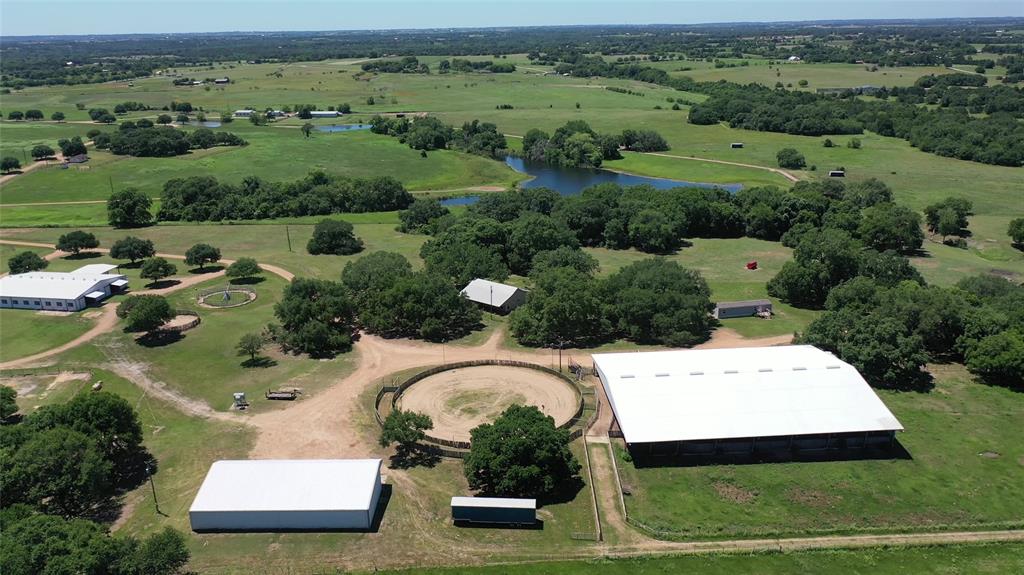 8616 FM 2502 Brenham, Texas In the rolling green hills outside of Brenham, TX, you will find some beautiful properties. The Wooten Ranch is one of these gems! Huge, majestic oak trees grace this 64+/- acres. Gorgeous hay fields are on both sides of the winding drive. The improvements are located under the trees and offer great privacy away from the main road. The 24 stall barn has an apartment and office. The barn is light and airy and has roomy stalls, tack rooms, storage areas and double wash racks. There are five pipe and horse wire traps with water and three have loafing sheds. A round pen and horse walker are by the barn. The covered arena offers a viewing stage, cattle pens and chute, good footing, mechanical flag and BigAss fans. A 140’ diameter cutting pen adjoins. Glorious, huge oaks and pecans grace the landscape. The 3/2.5 home has big porches, new appliances and beautiful trees. There is a year old mobile on the property for additional housing. Creek on the north end. Excellent hay/grazing.