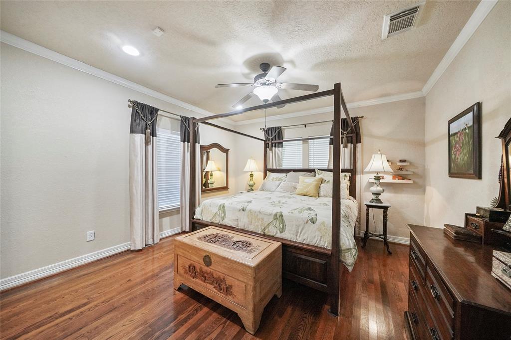 Spacious primary bedroom with loads of natural light, ceiling fan and gleaming wood floors.