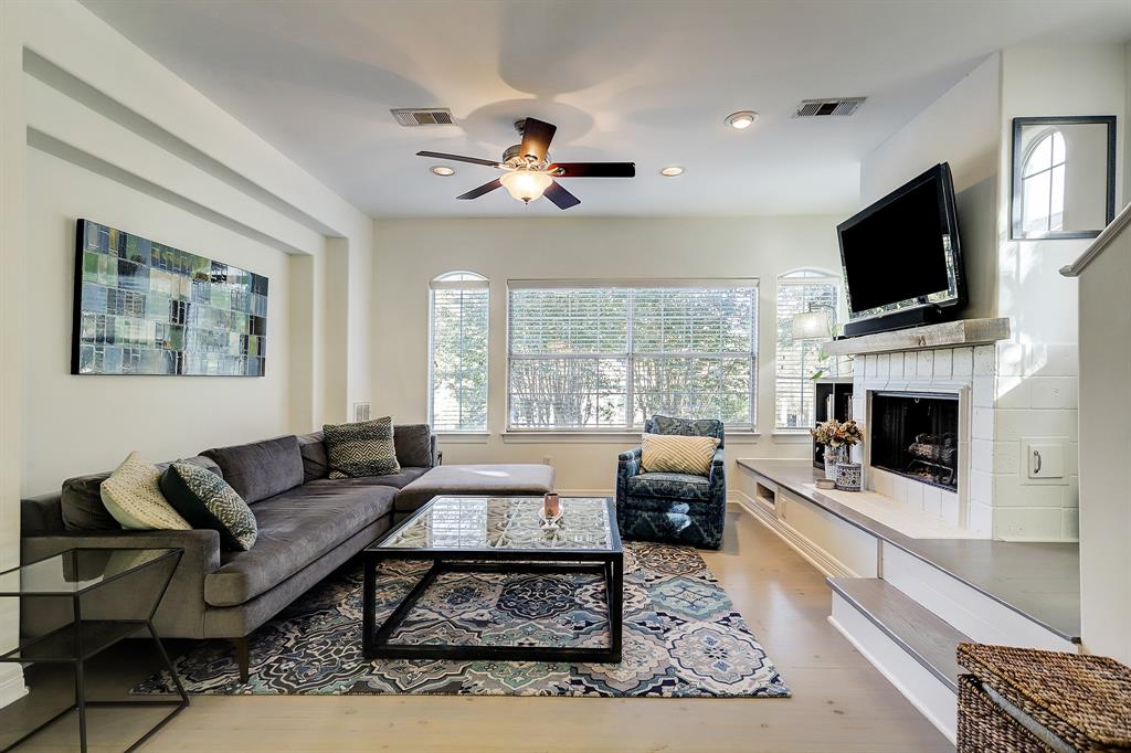 The living room includes a fireplace and looks out onto tree lined Harvard St.