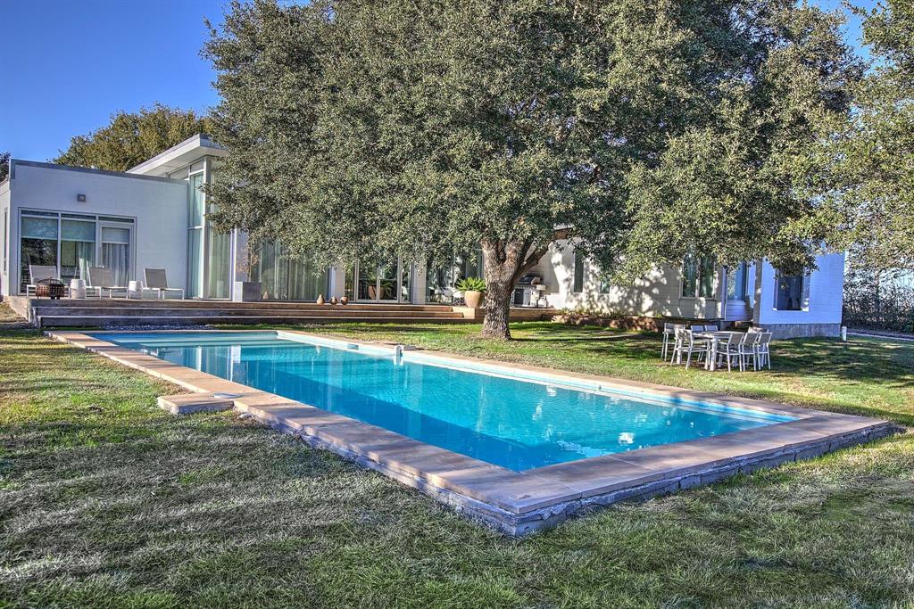 3141 W 3141 West Ueckert Road Bleiblerville, Texas MODERN TURNKEY INCOME PRODUCING PROPERTY ON 5 ACRES/POOL
Three bedrooms, study, three bathrooms
LOCATION: 20 minutes to Round Top, 15 minutes to Bellville, 90 minutes to Houston, 90 minutes to Austin
Blurring the line between a work of contemporary art and nature, this unexpected modern design by studioMET architects, frames captivating views allowing the natural scenery to filter in from all areas and become an integral part of the design of the home. Impressive steel and glass doors usher you into a Great Hall that integrates the dining area and gourmet kitchen with modern cabinetry and Carrera Marble countertops.
Floor to ceiling windows surround the open concept living area that is dramatically perfectly designed for admiring the evening sunsets. Inside, 15-foot-high walls of windows offer a pass-through to the serene views of the modern pool, specimen oak trees and natural meadow surrounding the home. Includes All furniture-some Artwork.