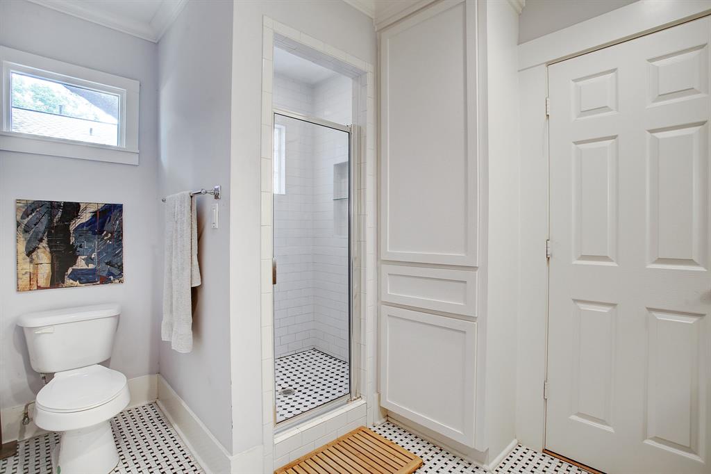 The primary bath includes a spacious shower stall with natural light, and a floor-to-ceiling linen/storage cabinet with a built-in laundry basket.