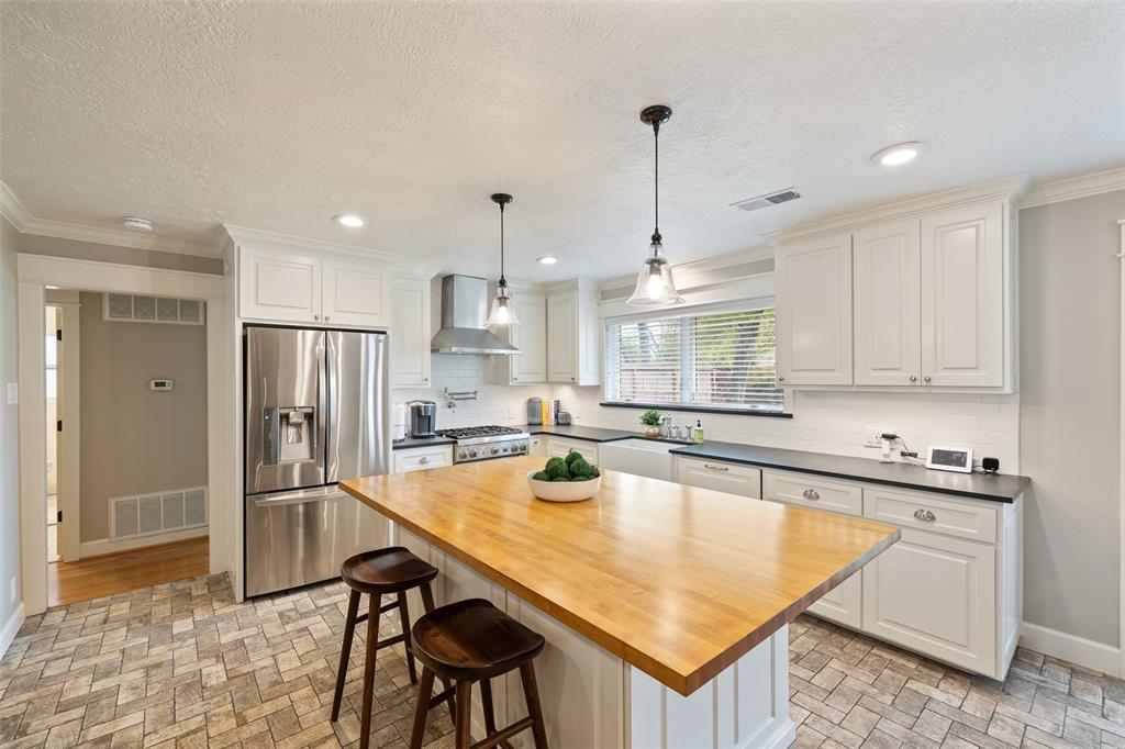 Spacious kitchen features Honed Black Brazilian slate countertops, deep apron front sink, and a LARGE butcher-block island with SO MUCH storage. Ceiling height custom cabinets add to open feel.