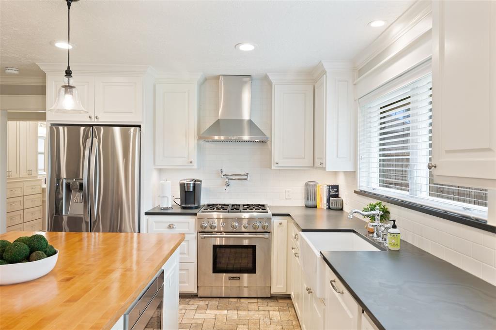 High-end appliances grace this kitchen including Thermador range, panel-front dishwasher, Sharp microwave drawer, and stainless refrigerator. Honed black Brazilian Slate countertops take things to the next level in the elegant kitchen space.