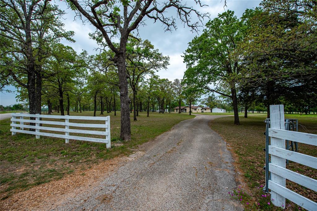 1542 County Road 113 Giddings, Texas Large brick home (2416 SF) situated on 3 unrestricted, fully fenced acres in a quiet area of Giddings. Numerous mature oak and pecan trees create a relaxing country setting. 3 bedrooms, 2 full baths with half bath off of the inside utility room. Two car tandem attached garage has been converted for extra living space with an additional half bath (two toilets and sink-space could be reconfigured to a shower to make a third full bath). Private space for guests, bonus room, workshop or a nice garage. Space also includes a kitchenette (stove may be excluded per seller). The main kitchen is open to den which has a wood burning fireplace, built-in shelves and large windows. Nice size pantry with counter space as well as a breakfast nook that overlooks a courtyard. There is also an office/hobby room and formal dining room, living room or office. Several walk in closets throughout the home. Outside has two additional buildings with concrete slabs, electricity and built in storage.