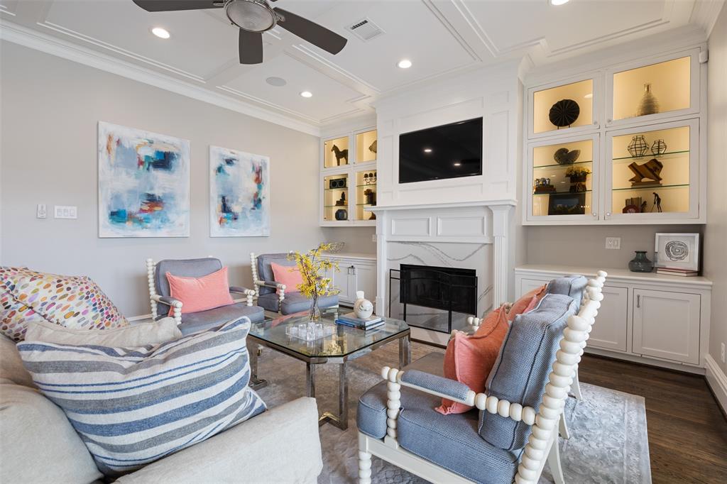 The living room also includes a coffered ceiling, built-in cabinets inlaid with glass, a fireplace, and a built-in, recessed TV.