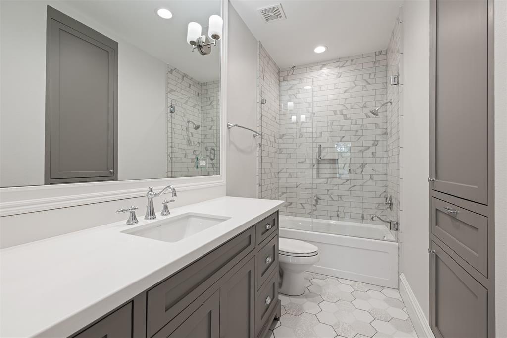 This gorgeous bathroom en suite incudes quartz counter-tops, custom cabinets with recessed doors and drawers, octagonal tile floor, tub/shower combo with Walker Zanger tile surround, custom glass, and linen closet with hamper.