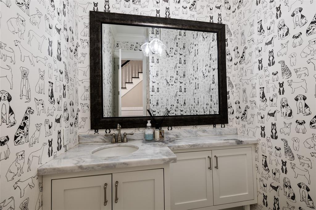 This half bath is located on the main floor and includes custom cabinetry, marble counter-tops, and an adorable wallpaper. It could be yours.