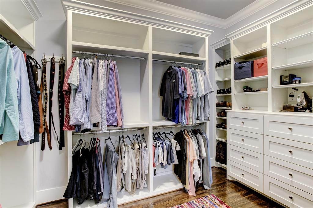 The primary walk-in closet is finished as finely as the rest of the house including hardwood floors, cabinetry with crown molding, dresser drawers, shoe shelves and hanging and stacking space for a variety of clothing items.
