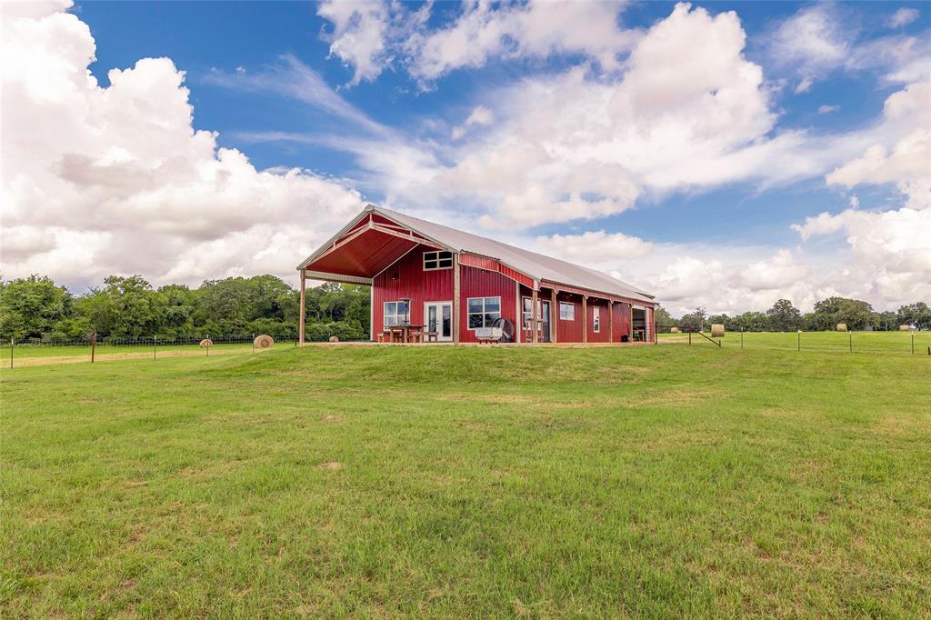 14133 Starview Lane North Zulch, Texas Come gaze at the stars on Starview Ln. This property is the perfect getaway, with 25 rolling acres to roam and a recently built 1560 Sqft, 3-bedroom, 1.5-bathroom barndominium with a 600 SqFt shop. The home boasts a wide-open floor plan with stunning vaulted wood ceiling, granite countertops, custom cabinets and hard surface floors throughout. Multiple large windows overlook the beautiful views or step outside onto 900 SqFt of wrap around porches. The 25 acres features scattered mature hardwood trees, fishing pond, improved pastures, multiple barns and Carter Creek traverses the back of the property. Don’t miss your chance to own this breathtaking property.