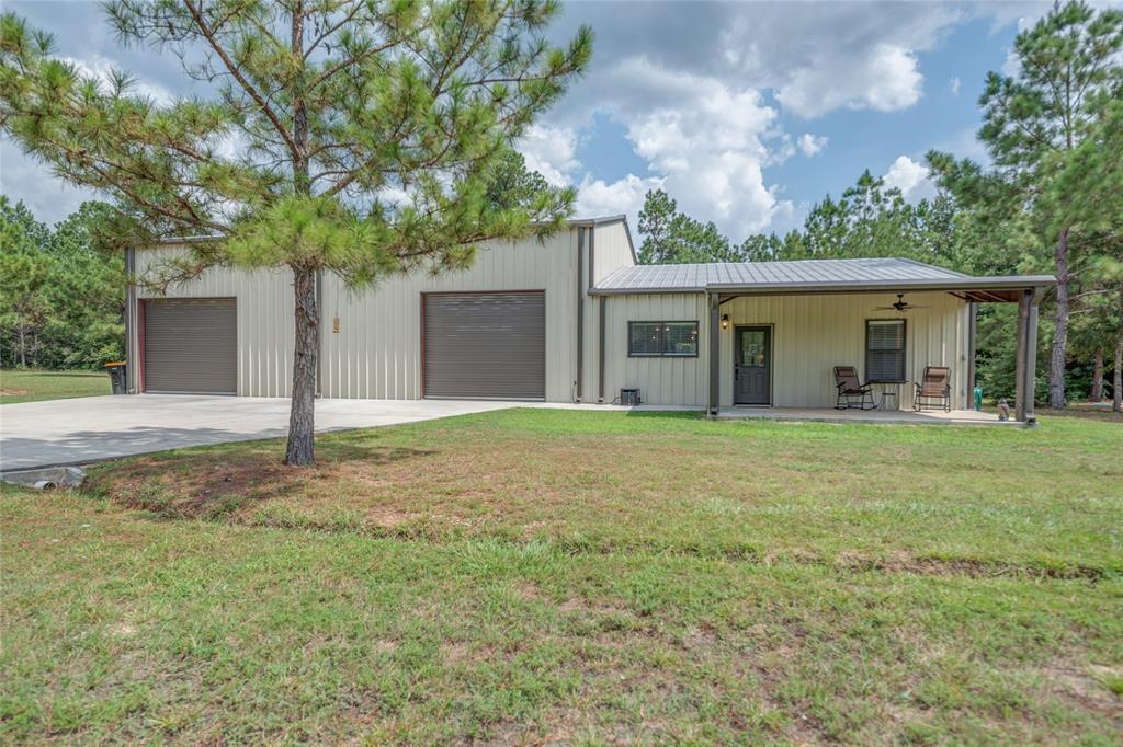 12906 S Lee Conroe, Texas 2 bed, 1.5 bath barndominium with 40'x50' INSULATED SHOP on 5.19 ACRES located in Timber Line Estates! The interior features crown molding, tile floors throughout with carpet in the bedrooms, recessed lighting and access to the shop. The kitchen features a large breakfast bar, an island, stainless appliances and looks into the living and dining rooms. The primary bedroom is spacious with a double door closet and easy access to the full bath. The secondary bedroom is just off of the dining room. The full bath features a double sink vanity, shower/tub combo and a large linen closet. The shop has 3 roll up doors for easy access, a 12 ft. Big Ass Fan, and a 12'x30' lean to with electrical hookup for RV. The property is partially fenced with a natural barrier at the back for privacy. 24'x24' steel carport with concrete pad. NO HOA, septic system and electrical large enough for additional 3,000 sq. ft. house.