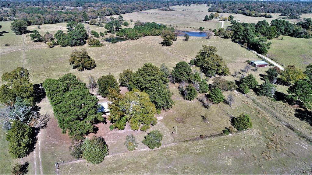 14242 FM 1280 Crockett, Texas 35.541 acres of pastureland with scattered pines and hardwoods makes this property exceptional for grazing livestock and hunting. If fishing is your favorite pastime, you will love the 2 ponds. There is also a water well in place for livestock and gardening. The 3/2.5 brick home sits nestled in towering trees. Welcoming front porch leads you into a very spacious and well-maintained home. The very large den will be your favorite gathering place with beautiful brick fireplace and room for everyone, a formal living area could be used for a study, media room or just that 2nd living room for overflow. The handy kitchen has stained cabinets, good counter space, dining area, and opens to a very large laundry room with plenty of room for storage. The master bedroom has a half bath while two guest bedrooms share a hall bath. The detached 2-car garage has a full bath. Property is fenced for cattle or horses with barn.