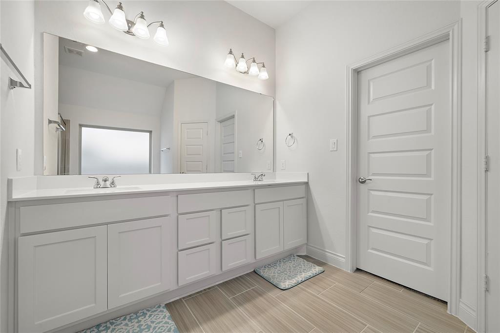 Double vanity and door that leads to walk-in closet.