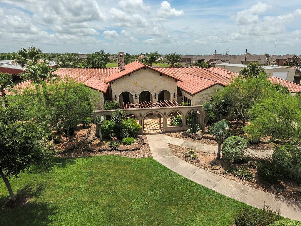 This remarkable Texas Hill Country type home encompassing 4.86 acres is situated near the end of a private street in coveted Rancho Viejo. An iron entry gate opens to spacious grounds and this sprawling one-story with front and rear courtyards. Three double entry doors lead to open living spaces with tall ceilings, quarried stone accent walls and stained-wood beams. Walls of glass open to expansive sheltered patios with an outdoor fireplace, enormous resort pool and spa with a Spindletop-style, vintage oil derrick, stucco cabanas and an elaborate summer kitchen. The interior floor plan rivals the exterior amenities. Its primary wing includes a secluded multi-room suite with bedroom, study and an extra room with pool access. The secondary wing has a game room, children's study and four bedrooms with en-suite baths. Spacious grounds allow for a barn with air-conditioned storage, a stocked pond, a pavilion and space for horses.