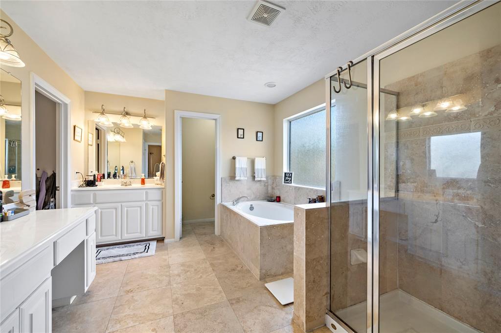 Primary bathroom with two separate counters and sinks as well as a large walk in closet.