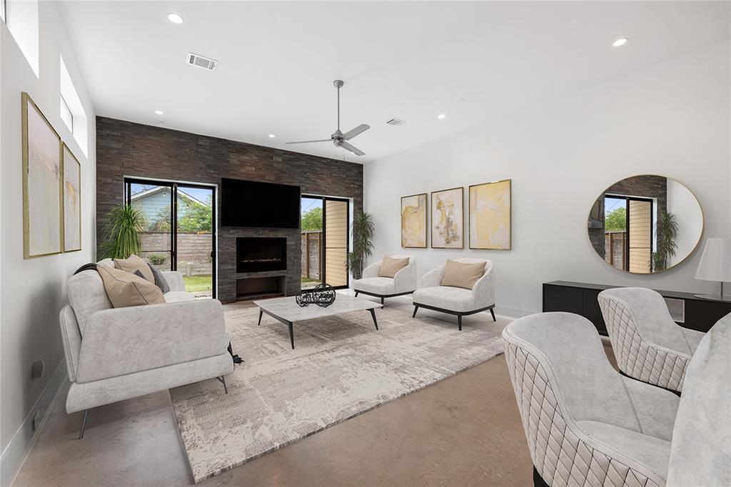 The living area is located directly off the covered back patio. The fireplace will provide both heat and ambiance on those cold winter nights. Outlets are tucked into the baseboards, not in the walls. This photo has been virtually staged