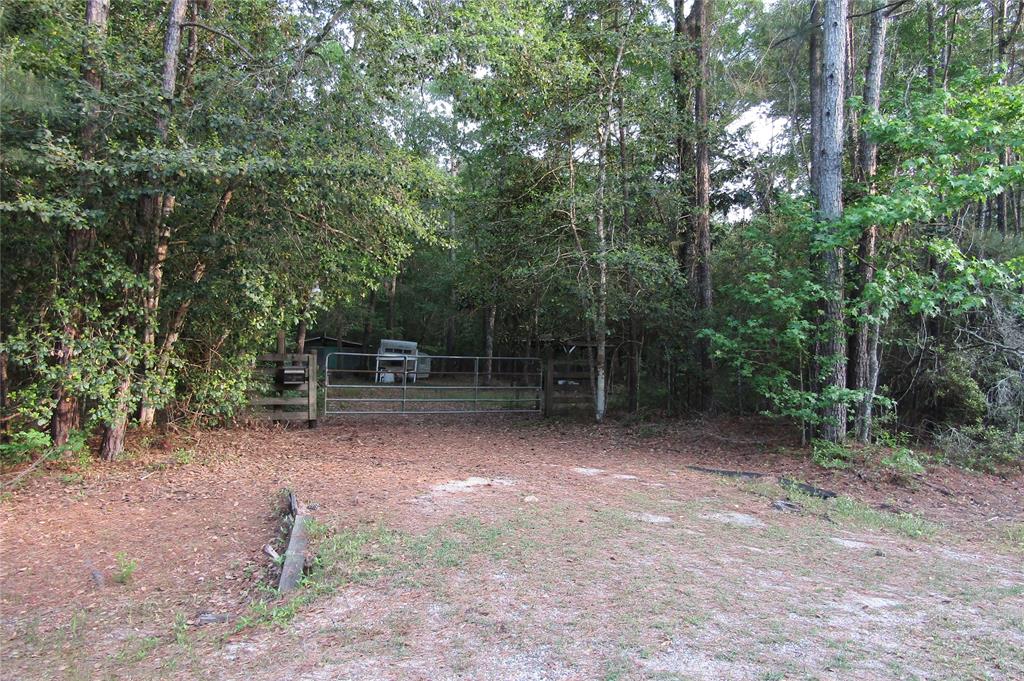 381 Whiskey Lane Cleveland, Texas 12.83+- wooded acres to build your dream home or satisfy all your hunting, fishing and outdoor desires! This property features 3 stands already set up to deer and hog hunt in. The picturesque pond is stocked with bass and various other fish. Trails will allow you to access this get away from the city life by foot or ATV. This property also features underground electrical to enjoy any creature comfort you may have and a bath house complete with septic services fed by public water. A 288 square foot storage building will make storing all you supplies easy AND a 200 square foot metal roof canopy will keep you and your family out of the elements. The campsite will be cleaned up prior to sale. Come check out this little haven just under an hour drive from the Houston area.