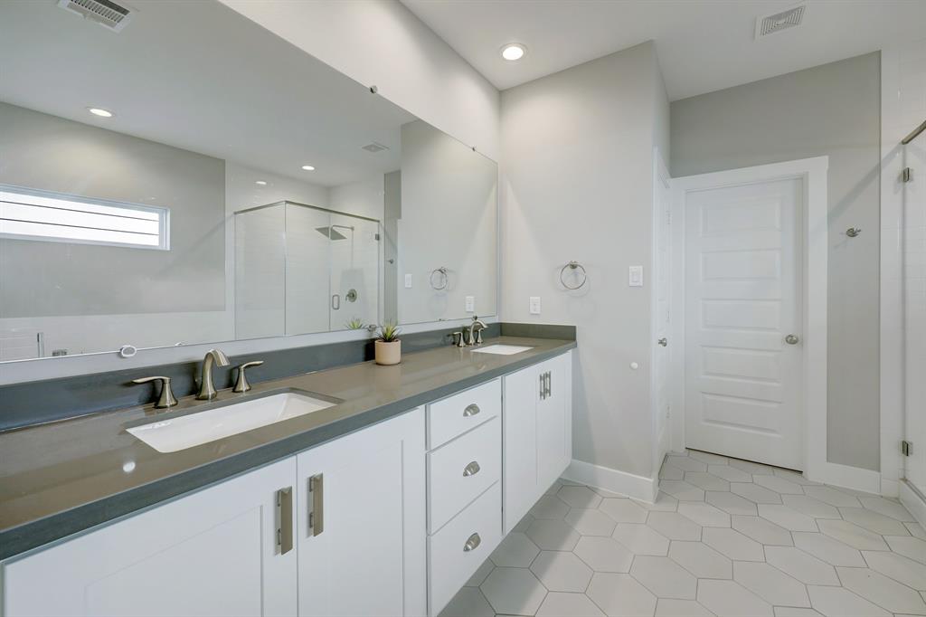 The primary bath has the same clean lines and finishes as the kitchen including quartz countertops.