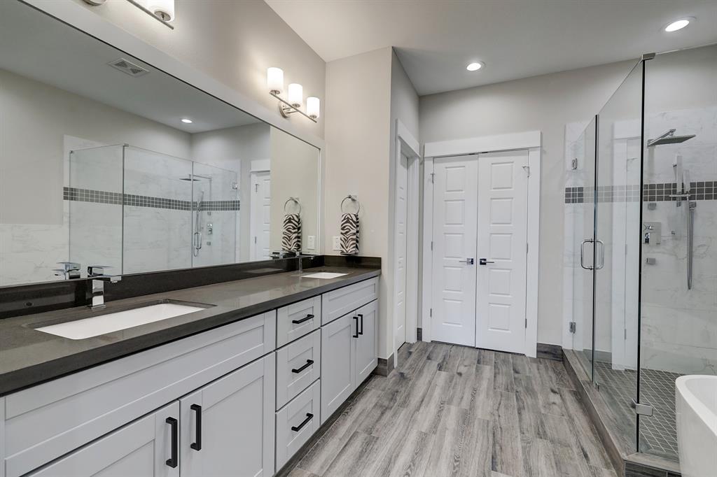 The primary bath is luxurious with a dual sink vanity and wood style tile floors.