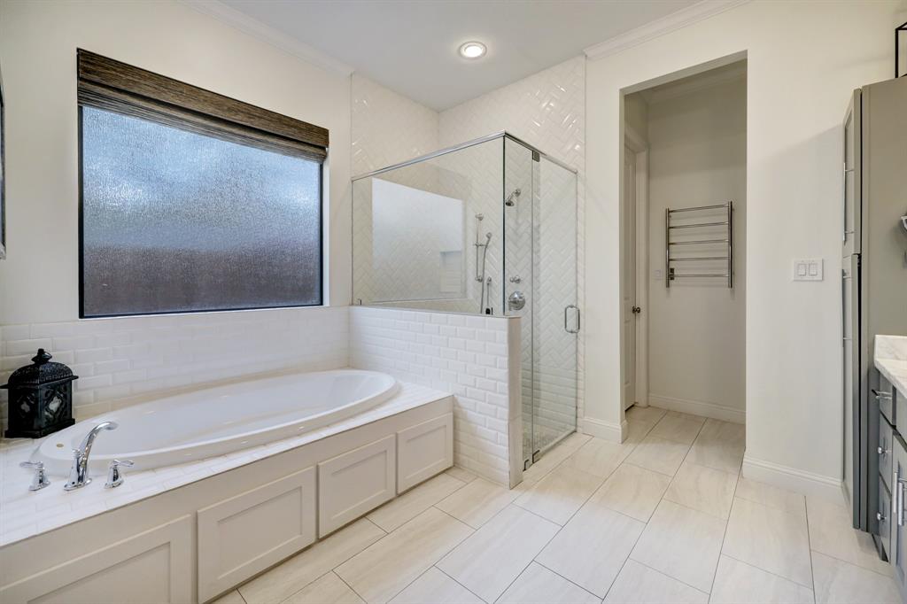 A large frosted glass window lets light stream in while providing privacy.  The shower stall is over sized with overhead and handheld sprayers.  Not photographed are two separated walk-in closets to either side of the chrome towel rack.