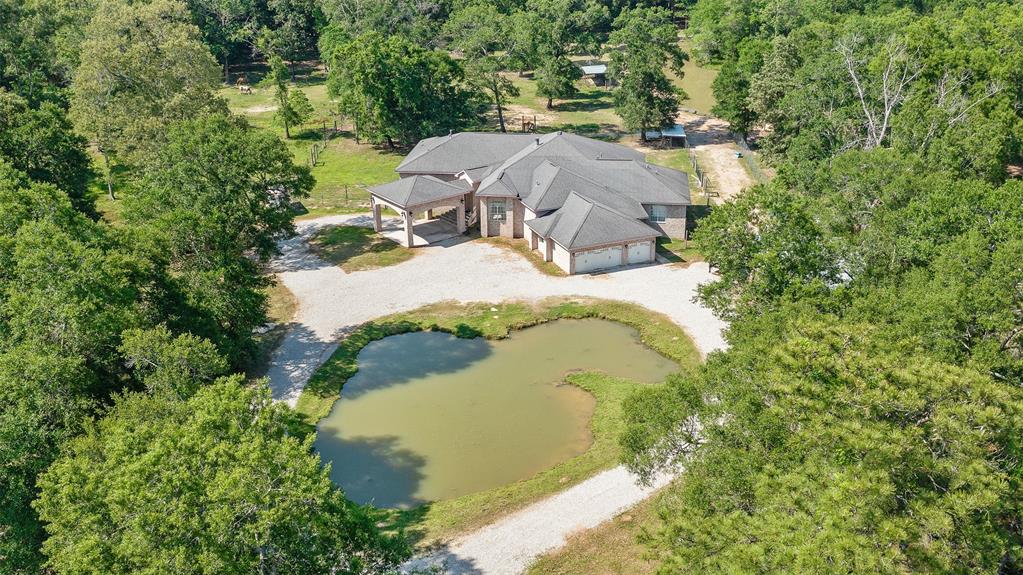 Country living is ideal on this 14 acre Texas Ranchette.  With 99 Grand Parkway nearing completion, this location is ideal for easy access to The Woodlands or any Houston metro area.  Enjoy the sunrise and sunsets on the 800 sq. ft. back porch with spectacular views of the land while the resident ducks swim in the stocked ponds.  This gorgeous home is great for gatherings inside and out and has wonderful views at any angle of the home.  There are  so many possibilities with this versatile piece of property.  Perfect for livestock, horses or your own little homestead/hobby farm.   From the moment you pull through the massive security gate, you will love the view of the home and land.  So much thought and detail has gone into this property, you do not want to miss out on this one of a kind treasure.