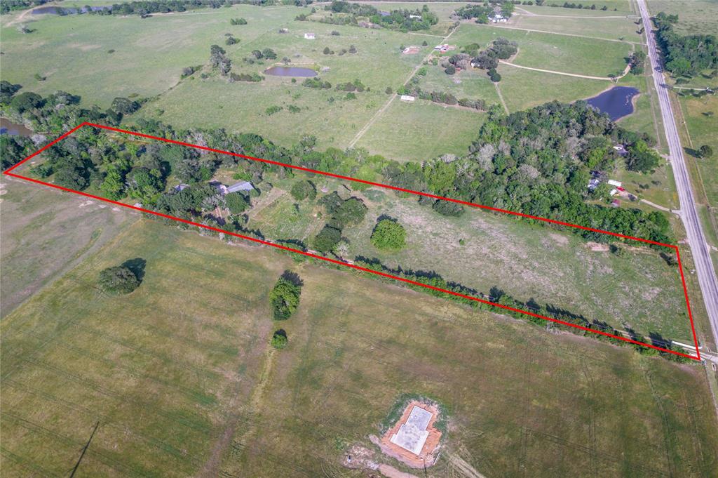Looking for that perfect small acreage in Austin County? Want a piece of country living just three miles out of Bellville? Then this is the tract for you!!!  The property features almost 11 acres of many mature trees, 2 ponds, a windmill, and road frontage on FM 529.  The 1,900 square foot home consists of three bedrooms and one bath. It features a large living room and a bright and airy kitchen. Both rooms are outfitted for wood burning stoves. The large master bedroom shares a hallway bathroom with the two additional bedrooms. The attached oversized 3 car garage has running water and a ½ bath that just needs to be finished out. The property also features several outbuildings including a wooden storage building, a metal shop, a metal portable building, a large equipment shed, and a livestock shed in the pasture. Property is perimeter fenced with an electronic gate for easy access. Call today and come see for yourself all that this property has to offer just minutes from Bellville.