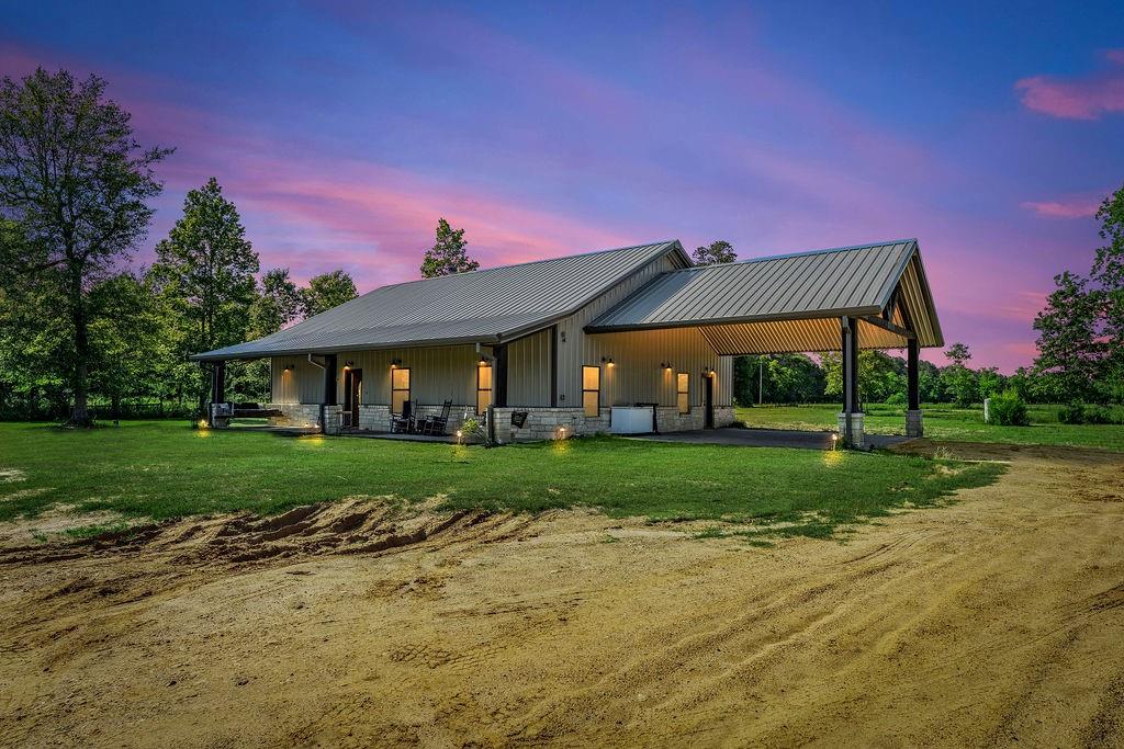 Situated in the low-tax area of Liberty County, this stunning 2,100 Sq Ft barndominium boasting 3 beds and 2 baths sits on 3 unrestricted acres! This custom built home features real wood cabinets, countertops, mantle, and flooring throughout. Upon entering the home you are greeted by soaring high ceilings featuring an accent wood beam. The living room boasts a wood burning stone fireplace + an elegant stone doorway. The open concept allows for a seamless transition to the kitchen, in which you will find butcher block countertops, a farmhouse sink, island + electric cooktop, and a breakfast bar. There is also a flex room that could be used as a home office or a formal dining. The primary bedroom is generously sized with dual sinks, a soaking tub, and a large walk-in shower. Additionally, there is a 16x12 safe room + a 1,800 Sq Ft upstairs area that is fully insulated, subfloored, and has electric. Exterior features include 2 ponds, a large covered front porch, and an attached carport!