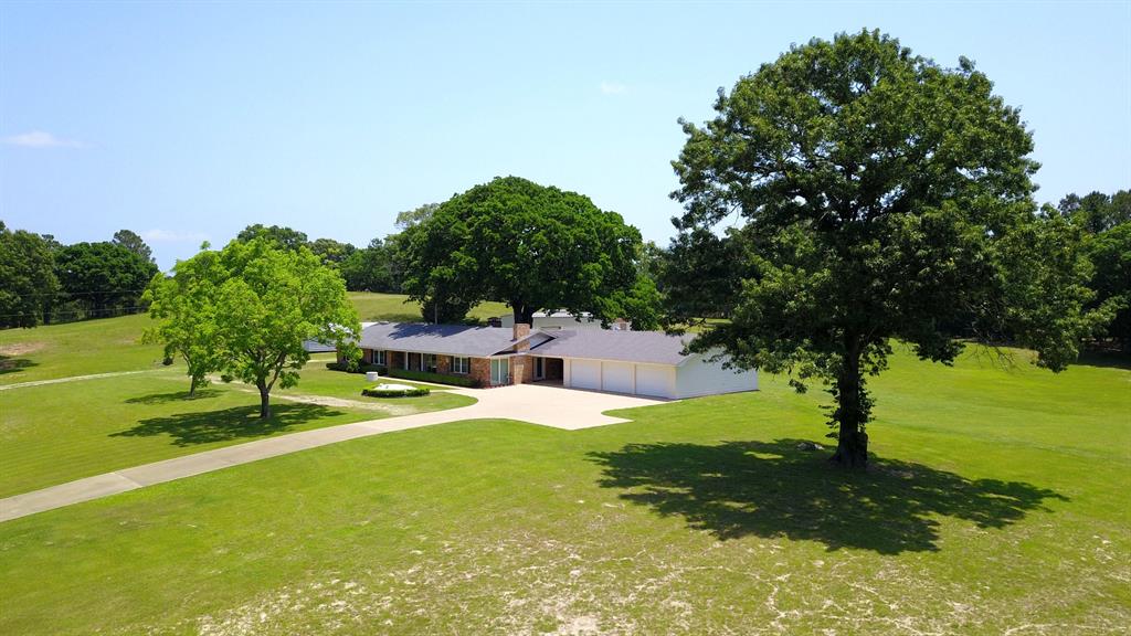 Updated country home on 14.5 acres of manicured rolling hills in East Texas! Escape the city and let yourself be drawn to the serenity of this beautiful setting. A large covered breezeway connects the well maintained home to an oversized 3 car garage. There are amazing views of the property surrounding you from this vantage point! With 2284 sq. ft., 3 bedrooms, 2.5 baths, large living area with WBFP with insert & blower, updated kitchen with custom cabinetry, island, & large pantry, plus a separate dining room with WBFP, you have plenty of space to enjoy family & friends. Experience the beauty of nature from the covered and open patio underneath the shade of a massive tree. Many updates - see extensive list in Associated Documents. A 1200 sq. ft. shop takes care of all the hobbies, toys, and equipment that you need. Underground storm shelter give you peace of mind. Easy living has been found - don't miss it!