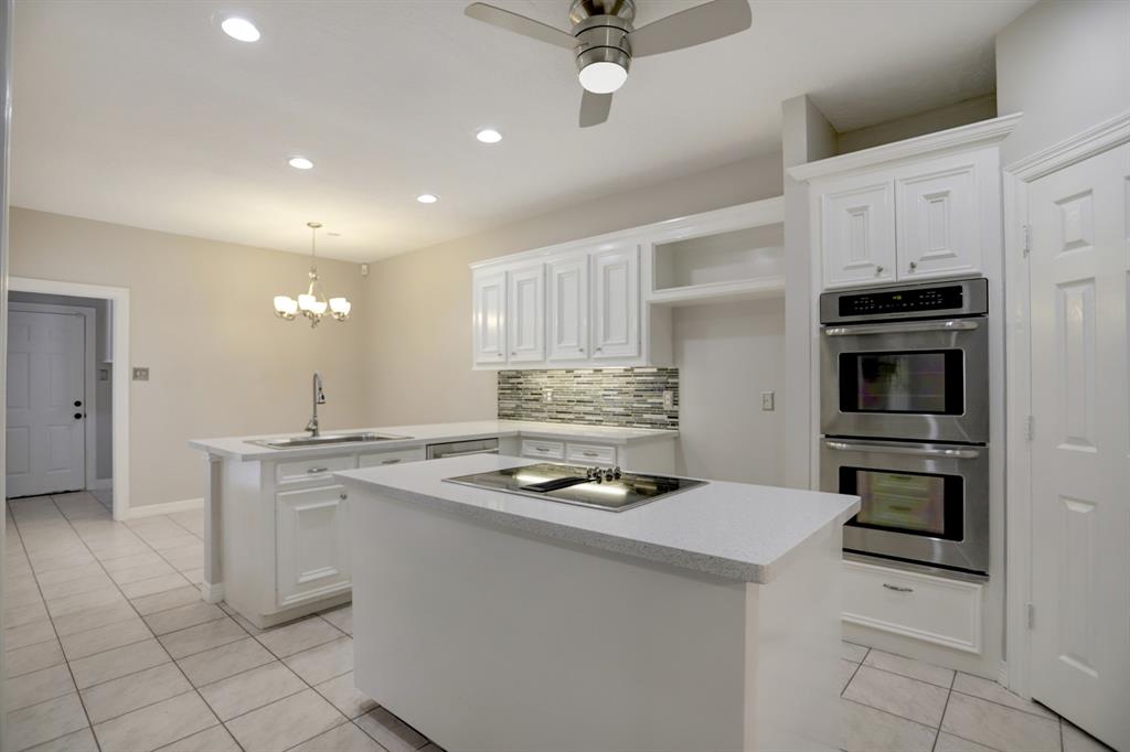 This island kitchen features stainless appliances, a double oven, accented backsplash and room for storage!