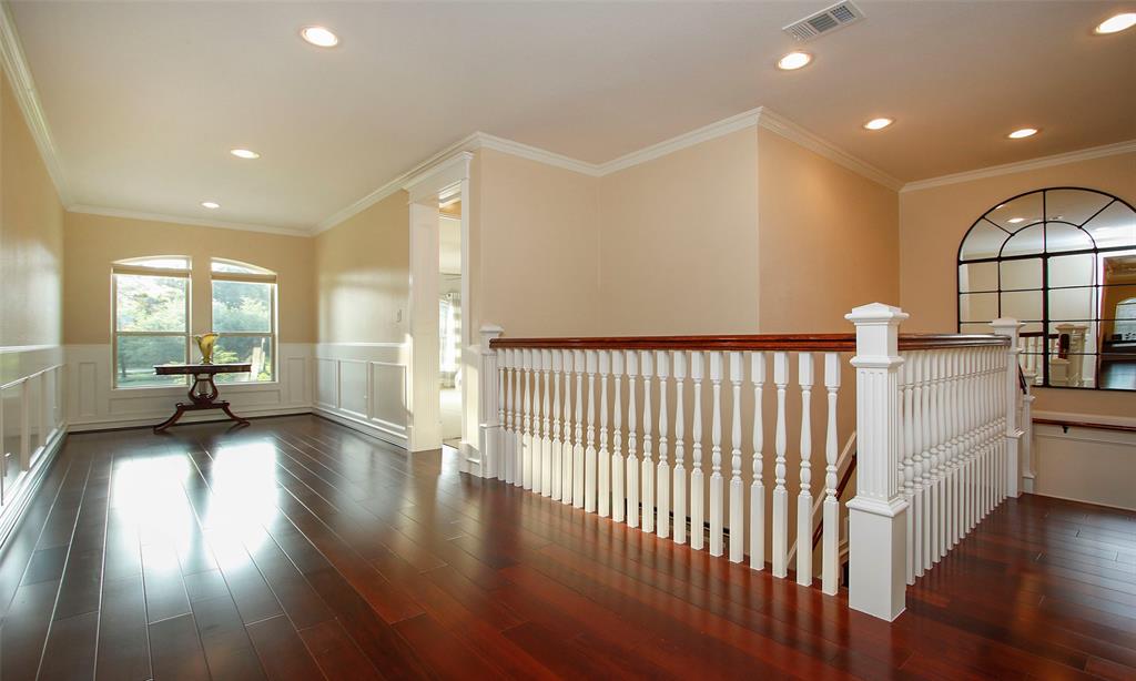 A view of the large wide hallway of the upstairs. Wainscot paneling and amazing decorative door casings, crown molding, and beautiful wood plank floors are provided.