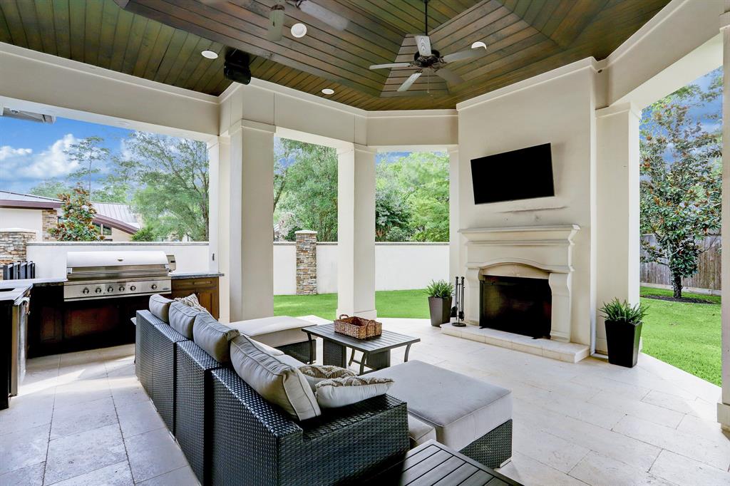Outdoor kitchen with sink refrigerator, smoker grill, gas fireplace and television