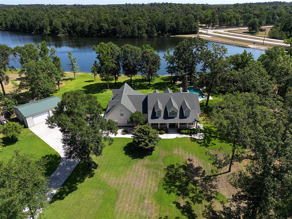 Beautiful Custom Home build by Thomas Green on 3+ waterfront acres with pool and small boat dock. Interior features large family room with high ceilings and walls of windows overlooking the lake and pool, game room and media room up, Huge Texas Basement/attic, incredible storage throughout, 3 AC systems, expansive rooms, all bedrooms down, custom built ins, Crown molding, large laundry room, kitchen features granite counters, High end stainless appliances, roll out shelves and deep drawers, double pantry. Large back patio, custom heated pool, Mueller Installed Metal workshop 40FT X 30 FT insulated on concrete slab, insulated 16 X 10 steel doors, dedicated meter, Private well for watering yard, wall heater in workshop, home has recent interior and exterior paint, 2 car oversize garage, Easy access to Conroe, The Woodlands and shopping and so much more!