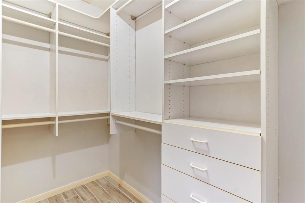 Walk-in closet with built-in storage shelves and drawers.