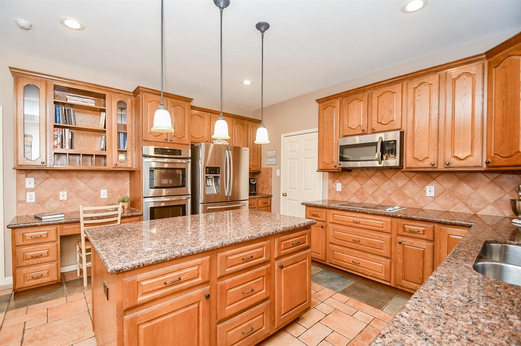 Stainless steel appliances add to the glow of this space, with a handy, built in desk and shelving above, for note making, while your culinary delights cook away!