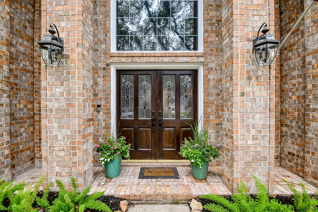 Sturdy, rich, double front entry doors are covered and embraced by brick surrounds, sparkling glass windows above, and hearty welcoming wishes!