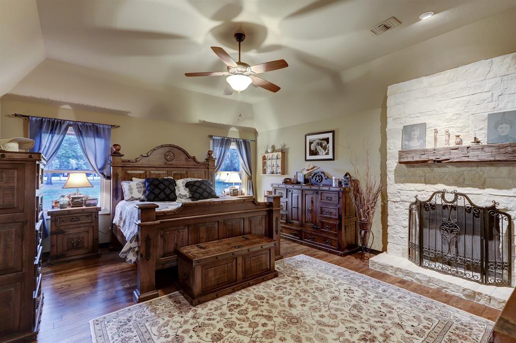The mater suite offers a peaceful retreat complete with beautiful views and fireplace. Note the high ceiling and wood type flooring.