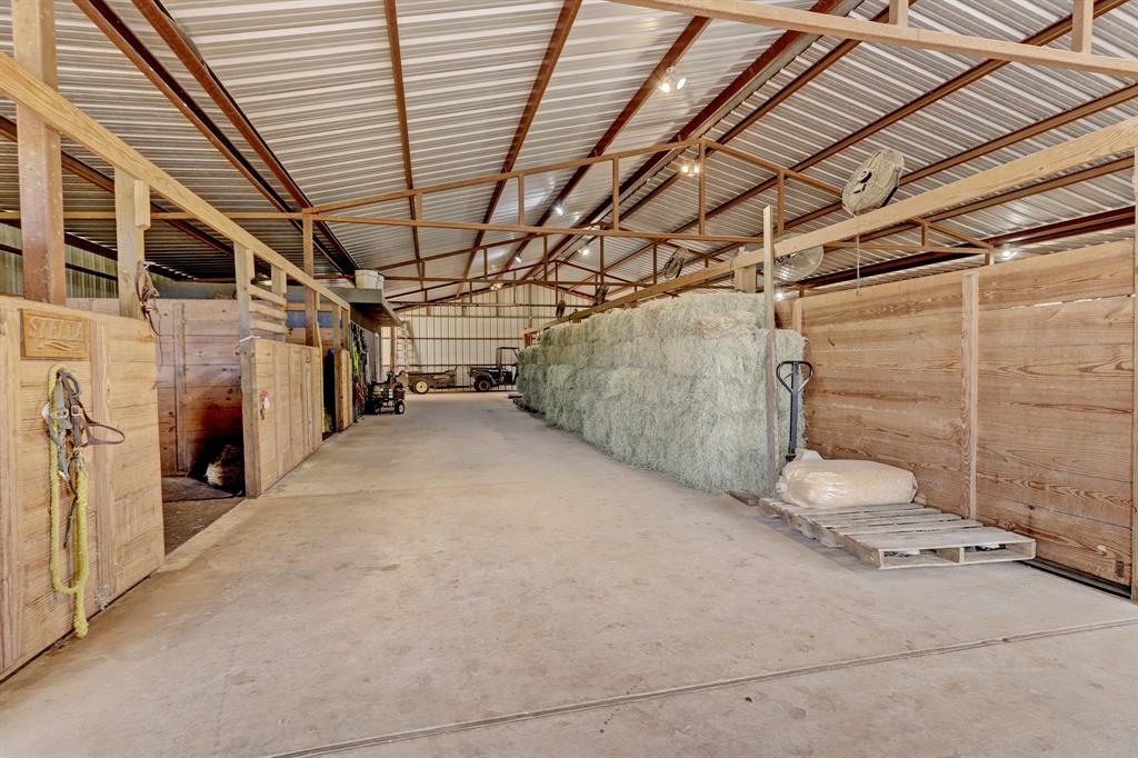 Wide aisles, implement and hay storage, fans at each stall. At the far end left is the tack room and main entrance. To the near left is one of two broodmare stalls.